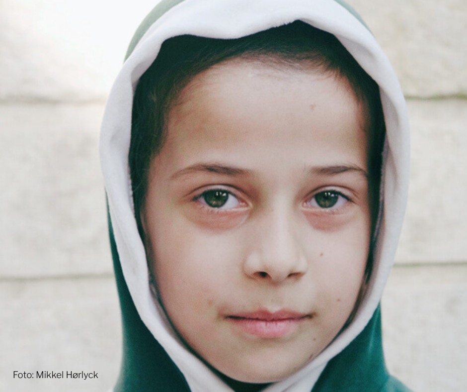 Pige i Aleppo, Syrien I Aleppo, Syrien, møder vi en pige. I hendes blik kan man ane et stille kald efter håb – et håb, der lever midt i en hverdag præget af krig og usikkerhed.