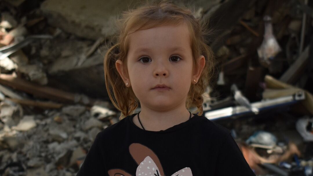 Lilje står foran et bombet hus i Ukraine. Sådan ser hendes hverdag ud nu. Hun ser håbefuldt mod dig.