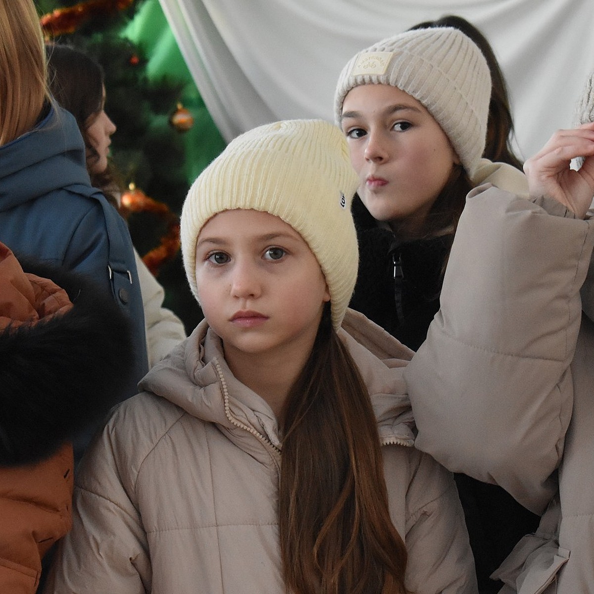 To ukrainske unge piger i hvide uldhuer og beige frakker.